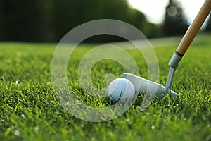 Hitting golf ball with club on green course, closeup. Space for text