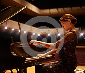 Hitting the right notes. Shot of a young woman playing the piano during a musical concert.