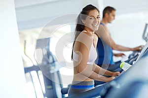 Hitting the treadmill. A young man and woman exercising on treadmills at the gym.