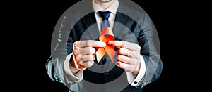 Hiv aids. Red ribbon in hiv world day  on dark background. Man holding awareness aids and cancer symbol. Health