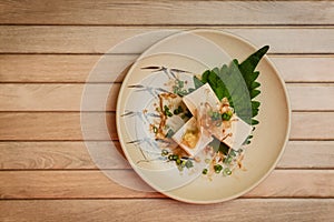 Hiyayakko Japanese tofu. Japanese cold tofu with soy sauce, green onion, bonito flakes and oba leaf in a ceramic bowl.