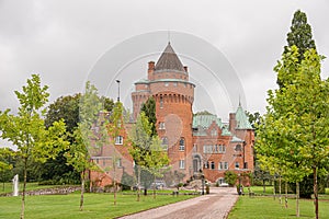 Hjularod castle is a romantick red castle inside a park on a green lawn photo
