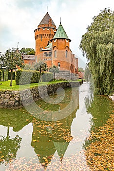 Hjularod is a romantic red castle with tall towers reflecting in the moat