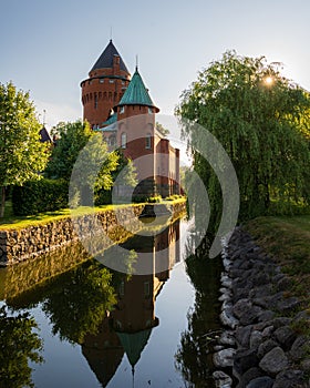 HjularÃ¶d castle relfecting in the moat surrounding it during golder hour
