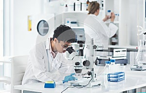 Hmm this is an interesting finding. an attractive young female scientist looking through a microscope in a laboratory