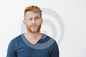 Hmm let us imagine. Portrait of dreamy cute adult redhead male with beard, looking up with one eye closed, lifting