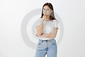 Hmmm, let me think about it. Portrait of serious focused fashionable european woman in jeans and t-shirt, holding hand