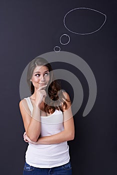 Hmmm, what should I do. Cute young woman standing and thinking with a chalk thought bubble above her head.