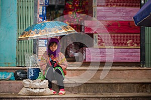Hmong hill tribe girl sits at market with umbrella