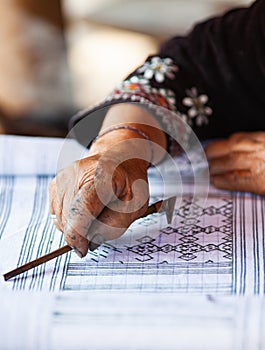 hmong woman drawing the patterns for beautiful handmade fabrics of hill tribe people of Thailand