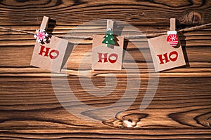 Ho ho ho phrase on little kraft paper stickers hanging on a rope on wooden clothespins. Santa Claus.  Rustic Christmas decoration