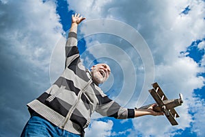 hoary senior man on sky background. senior man at retirement. senior retired man with toy plane