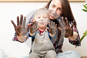 Hobbies at home gardening learning botany - young mother and child showing hands covered in dirt