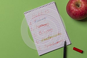 Hobbies list wrote on a spiral notebook. Above view with copy sp