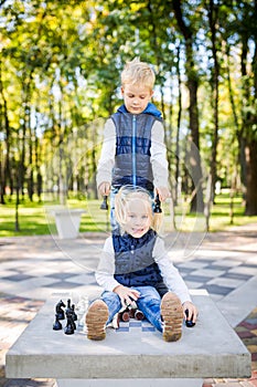 Hobby of Children, Boy and Girl Playing Chess. Funny little brother and sister playing outdoor chess in the park on a public site