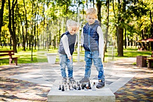 Hobby of Children, Boy and Girl Playing Chess. Funny little brother and sister playing outdoor chess in the park on a public site