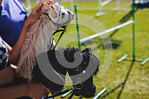 Hobby horsing competition on a green grass, hobby horse riders jumping, equestrian sport training with stick toy horses in a