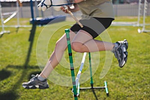 Hobby horsing competition on a green grass, hobby horse riders jumping, equestrian sport training with stick toy horses in a