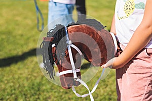 Hobby horsing competition on a green grass, hobby horse riders jumping, equestrian sport training with stick toy horses in a