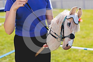 Hobby horsing competition on a green grass, hobby horse riders jumping, equestrian sport training with stick toy horses in a