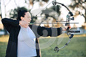 Hobby, learning and woman playing archery as a sport, outdoor activity and game in nature of France. Training, practice