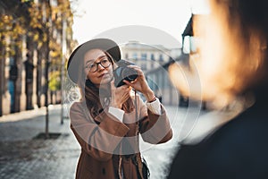 Hobby photographer concept. Outdoor lifestyle portrait of pretty young woman in sun city in Europe with camera travel photo