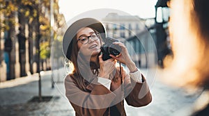 Hobby photographer concept. Outdoor lifestyle portrait of smiling  woman having fun in sun city in Europe with camera travel