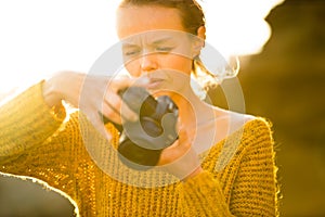 Outdoor lifestyle portrait of young woman taking photos with her mirrorless camera