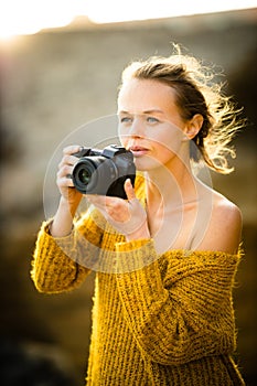 Outdoor lifestyle portrait of young woman taking photos with her mirrorless camera