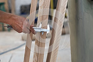Hobby wood concept. Cropped photo of cabinetmaker handcraft measures thickness of wood with a special device in hand to make