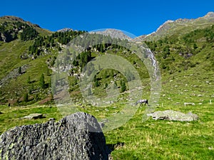 Hochschober - Horses grazing on alpine meadow with scenic view of idyllic waterfall and majestic mountain peak of Hochschober