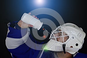 Hockey goalie drinks water.Detail of a male face in a white goalie hockey mask.