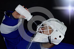 Hockey goalie drinks water.Detail of a male face in a white goalie hockey mask.