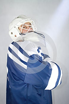 The hockey goalie stands sideways and has his hands folded.