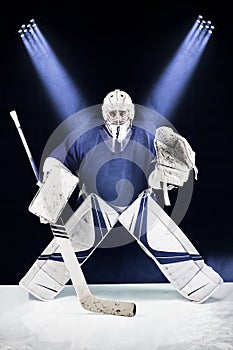 Hockey goalie stands in the spotlight ready to catch the puck.