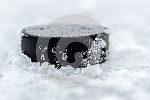 Hockey puck lies on the snow close-up