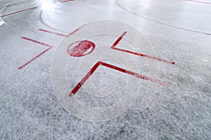 Hockey rink with faceoff spot on freshly resurfaced ice with marks of water