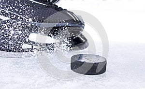 Hockey skate with snow splashes and puck
