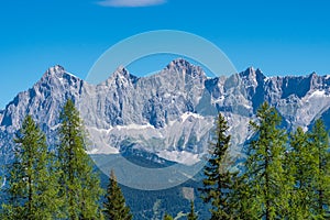 Hohe Dachstein mountain range in Austria with green trees in the