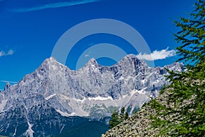 Hohe Dachstein mountain range in Austria with green trees in the