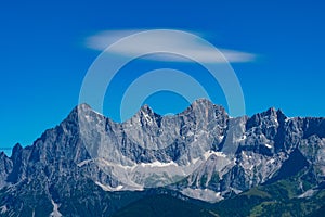 Hohe Dachstein mountain range in Austria and a white soft cloud