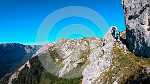 Hohe Weichsel - Couple with a hiking backpacks climbing to the of a big boulder on the way to Hohe Weichsel in Austria