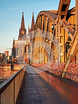 Hohenzollern Bridge, also known as the Bridge of Love, and the Cologne Cathedral in the rays of the rising sun. Germany