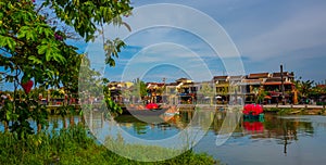 Hoi An Vietnam. May 05, 2019: Vietnamese wooden boat on the The Bon river with old yellow buildings ancient town.