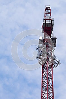 Hoisting crane used against a cloudy blue sky