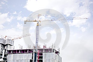 Hoisting cranes working building construction on bright blue sky and big cloud background