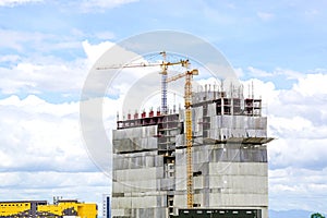 Hoisting cranes working building construction on bright blue sky and big cloud background