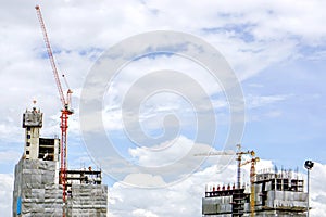 Hoisting cranes working building construction on bright blue sky and big cloud background