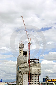 Hoisting cranes working building construction on bright blue sky and big cloud background