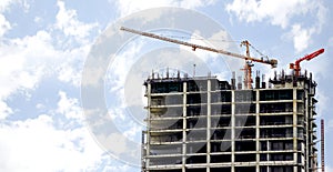 Hoisting cranes working building construction on bright blue sky and big cloud background